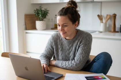 Femme concentr&eacute;e sur son ordinateur dans une cuisine moderne